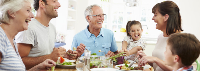 Multi Generation Family Eating Meal Around Kitchen Table